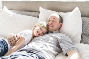 Father and daughter enjoying time in white bed