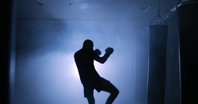 Silhouettes of a boxer in a dark smoky room