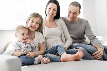 young family at home having fun on sofa
