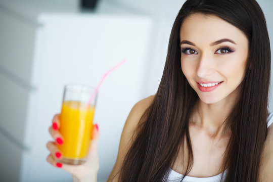 Young woman enjoying a glass of orange juice in the morning as she relaxes sitting on her bed in a healthy diet concept