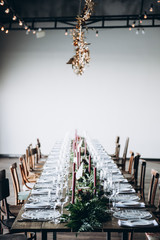 A festive table with crystal plates, glasses and cutlery, and decorated with candles and greenery. Photo with blurred background