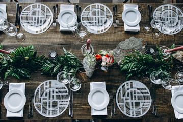 Festive banquet. Elements of decor. Crystal round plates, cutlerys, greeners and a glasses on a...