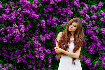 Happy beautiful young woman with long hair in a blooming spring Park, the charming girl in a white dress with bright flowering trees, the girl on the background of flowering gardens