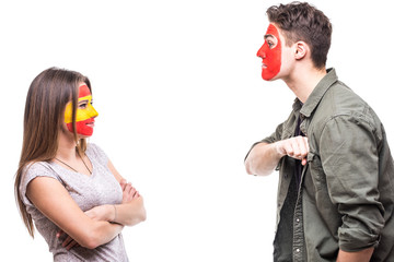 Handsome man supporter fan of Portugal national team painted flag face demonstrate loyal to woman supporter fan of Spain national team. Fans emotions.