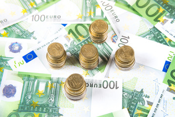 Group of coins on one hundred euro banknote background