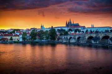 Skyline of Charles bridge and Prague castle on Vltava river during afternoon. Storm clouds with red color. Old Town, Prague, Europe.