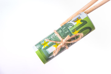 Obraz na płótnie Canvas Pack of one hundred euro banknotes tied up with a rope and hold them with chinese sticks isolated on white background