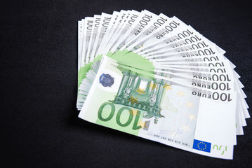 Fan of one hundred euro banknotes money on black background