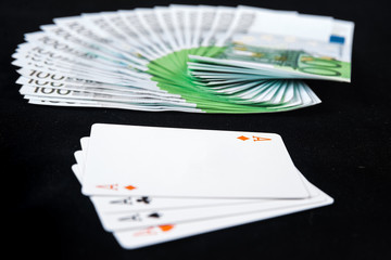 Fan of one hundred euro banknotes money on casino poker with four aces card on black background