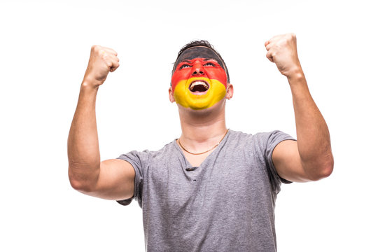Handsome man supporter fan of Germany national team with painted flag face get happy victory screaming into a camera. Fans emotions.