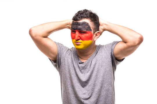 Handsome man supporter fan of Germany national team painted flag face get unhappy sad frustrated emoitions into a camera. Fans emotions.