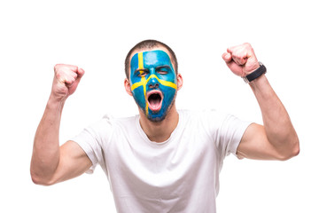 Handsome man supporter fan of Sweden national team with painted flag face get happy victory screaming into a camera. Fans emotions.