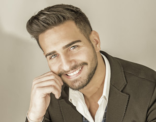 Trendy young man in studio shot wearing elegant vest and white shirt, looking at camera smiling