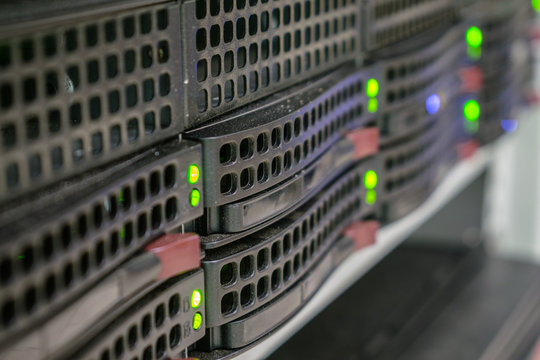 A powerful server is located in the computer room of the computer center. Computing center for data processing. Green LED lights on hard drive slots. Selective focus