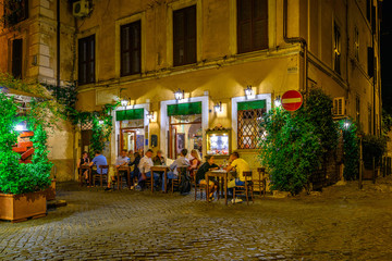 Naklejka na ściany i meble Night view of old street in Trastevere in Rome, Italy. Trastevere is rione of Rome, on the west bank of the Tiber in Rome, Lazio, Italy. Architecture and landmark of Rome