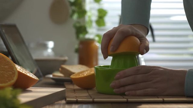 Woman preparing an healthy orange juice for breakfast