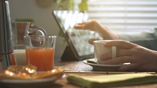 Woman having breakfast and using a tablet