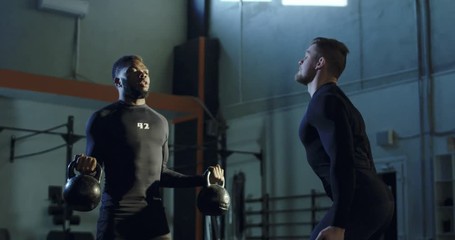 Man in sportswear helping African-American sportsman with bicep pumping exercise encouraging inspiration during workout. Shot on Red cinema camera.