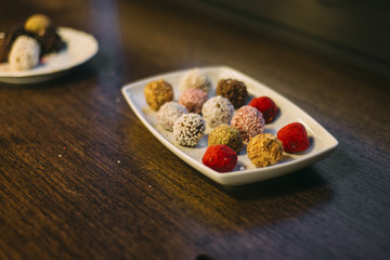 truffle candy lie on white plate on the wooden table with nuts
