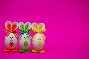 Multicolored funny eggs in the form of cute bunny on pink background. Happy easter. Festive decoration