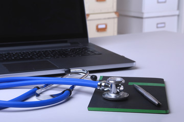 Workplace of doctor with laptop, stethoscope, RX prescription, glasses and notebook on white table. Copy space.