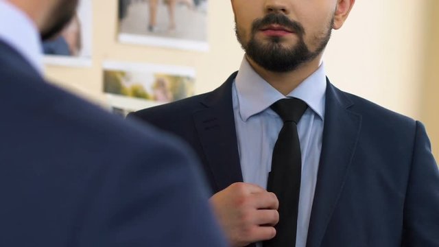 Man looking at mirror reflection trying on business suit, first day at new work