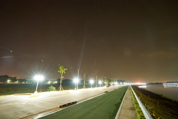 the road with half green way for bicycle and normal way for car or motorcycle have a big barrier (dangerous) at the center for block between bicycle and car at night. long exposure light.