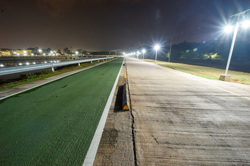 the road with half green way for bicycle and normal way for car or motorcycle have a big barrier (dangerous) at the center for block between bicycle and car at night. long exposure light.