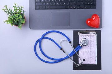 Workplace of doctor with laptop, stethoscope, RX prescription, glasses and red heart and notebook on white table. top view. Copy space.