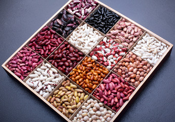 Different types of legumes beans. In wooden box.Varieties of beans.Small red bean,Scarlett runner bean Phaseolus coccineus ,butter bean,kidney bean,pinto and other sorts of beans.Top view.
