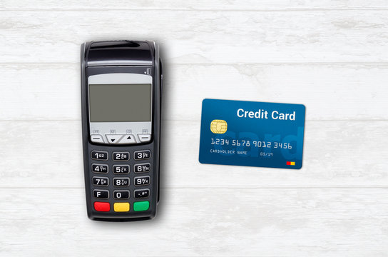 Payment terminal and credit card on wooden background