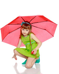 The girl closed from the sun and rain under a red umbrella.
