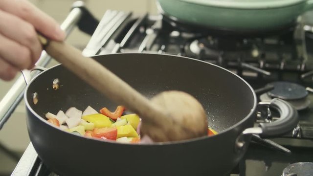 Man Sauteing Multi Colored Vegetables In Saucepan On Stove