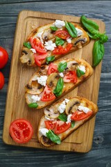 Italian antipasti bruschetta with chopped tomatoes, champignons, ricotta and basil, healthy and delicious summer snack, view from above