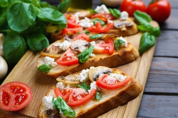 Tasty homemade Italian antipasti bruschetta with chopped tomatoes, champignons, ricotta and basil, healthy and delicious snack close up