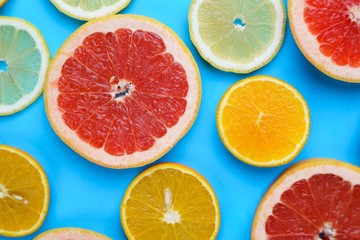 Citrus slices on blue background, flat lay. Bright vibrant summer background