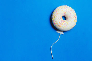 Donut on Blue, Creative Food Minimalism, Donut in Shape of Balloon in Sky, Top View with Copy Space, Toned