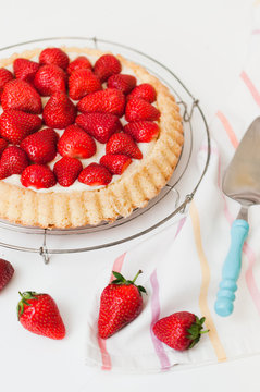Top view of traditional German strawberry cake with genoise sponge base and French vanilla custard pudding, called creme patissiere, for birthday or garden party on white wooden table
