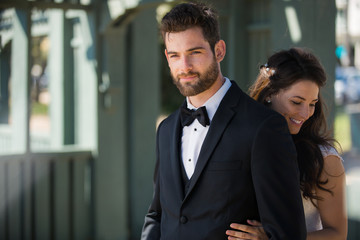 Beautiful newlywed couple dressed sharp and stylish, smiling together outdoors
