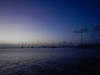Beautiful romantic sunset on the Caribbean island of Martinique: fisher boat, cloudy purple sky and...