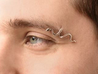 Young man with pierced eyebrow on light background, closeup
