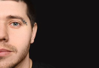 Fototapeta premium Young man with pierced eyebrow on black background