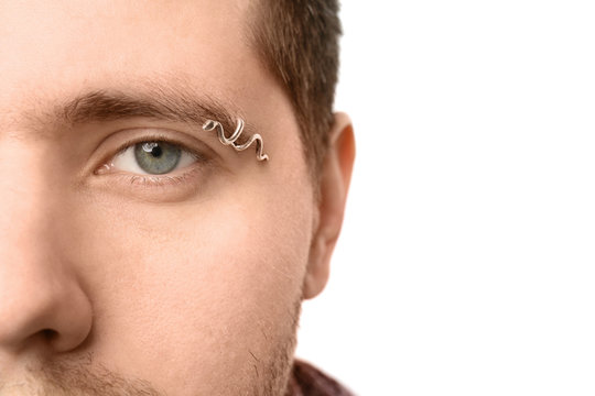 Young Man With Pierced Eyebrow On Light Background, Closeup