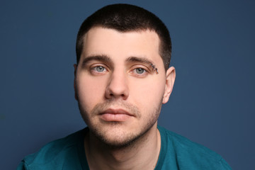 Fototapeta premium Portrait of young man with pierced eyebrow on color background