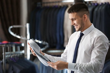 Fototapeta premium Young man choosing shirt to match his suit in boutique