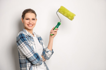 Young female decorator with paint roller on white background