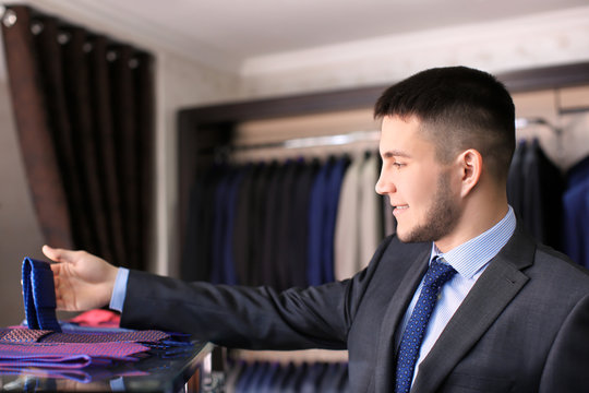 Man choosing necktie to match his suit in boutique