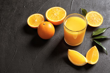 Glass of orange juice and fresh fruits on grey background