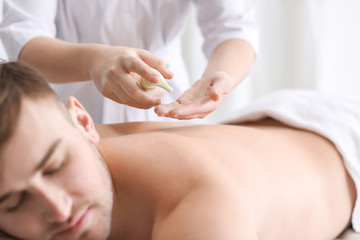 Obraz na płótnie Canvas Young man having massage in spa salon