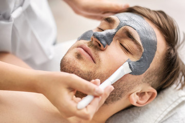 Obraz na płótnie Canvas Man having cosmetic mask in spa salon